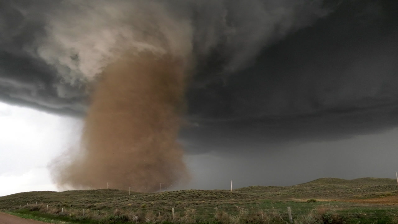 Large, swirled tornado crosses over sand hills, Wray, Colorado