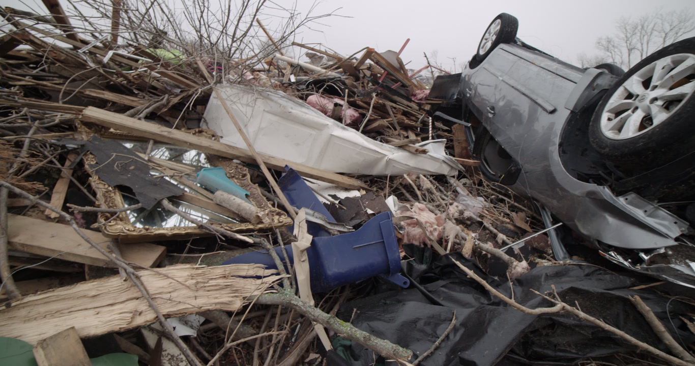 Tornado damage and aftermath - Close-up pan of upside down car on debris pile, 4K