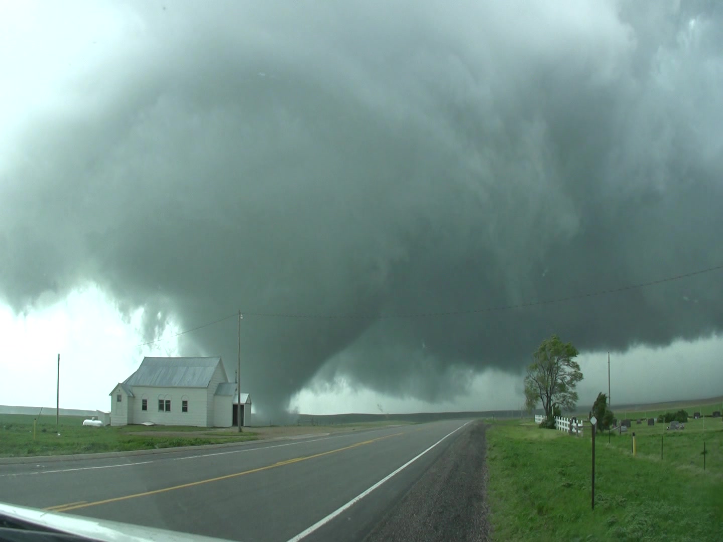 Tornado - Cone shaped tornado tracks behind white church and over rural highway