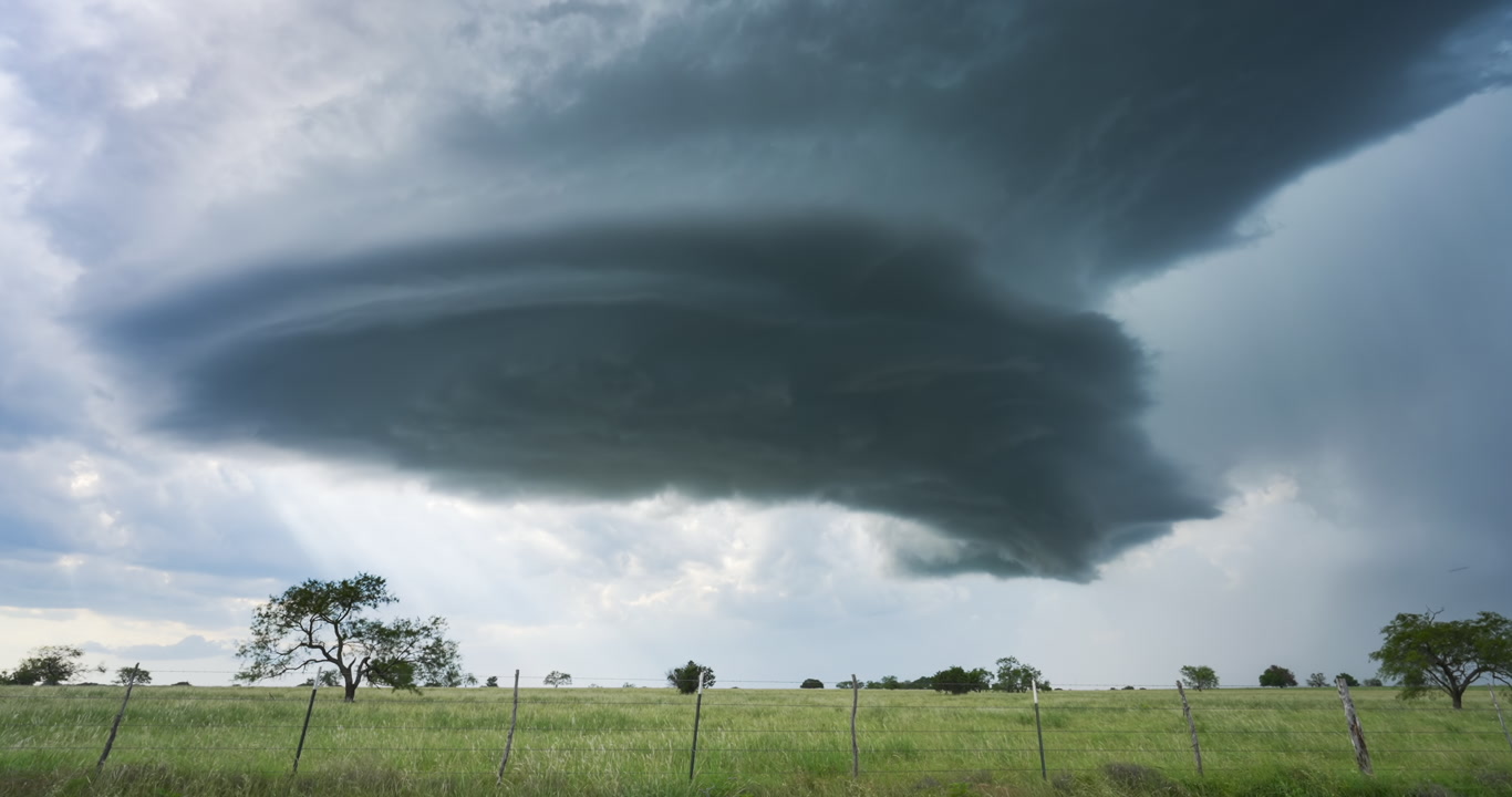 Dark, alien like supercell spins and moves over green prairie, time-lapse, 4K