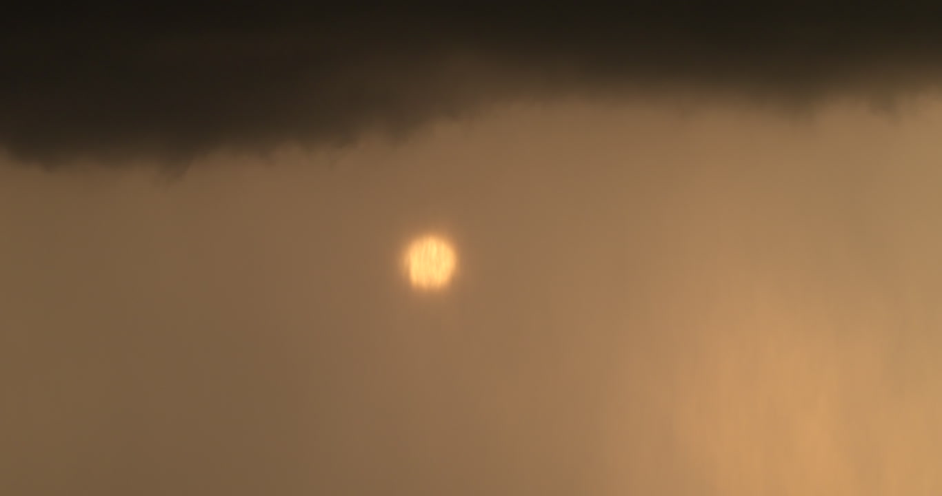Rain falls in front of orange sun, sky only, 4K