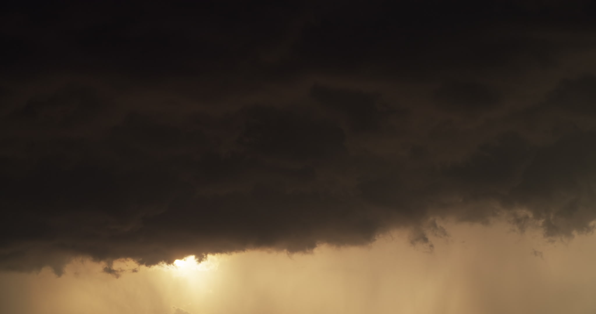 Sun appears from below dark, inky storm clouds, late day, 4K