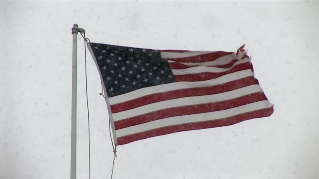 American flag blows as snow falls - winter storm, HD 1080