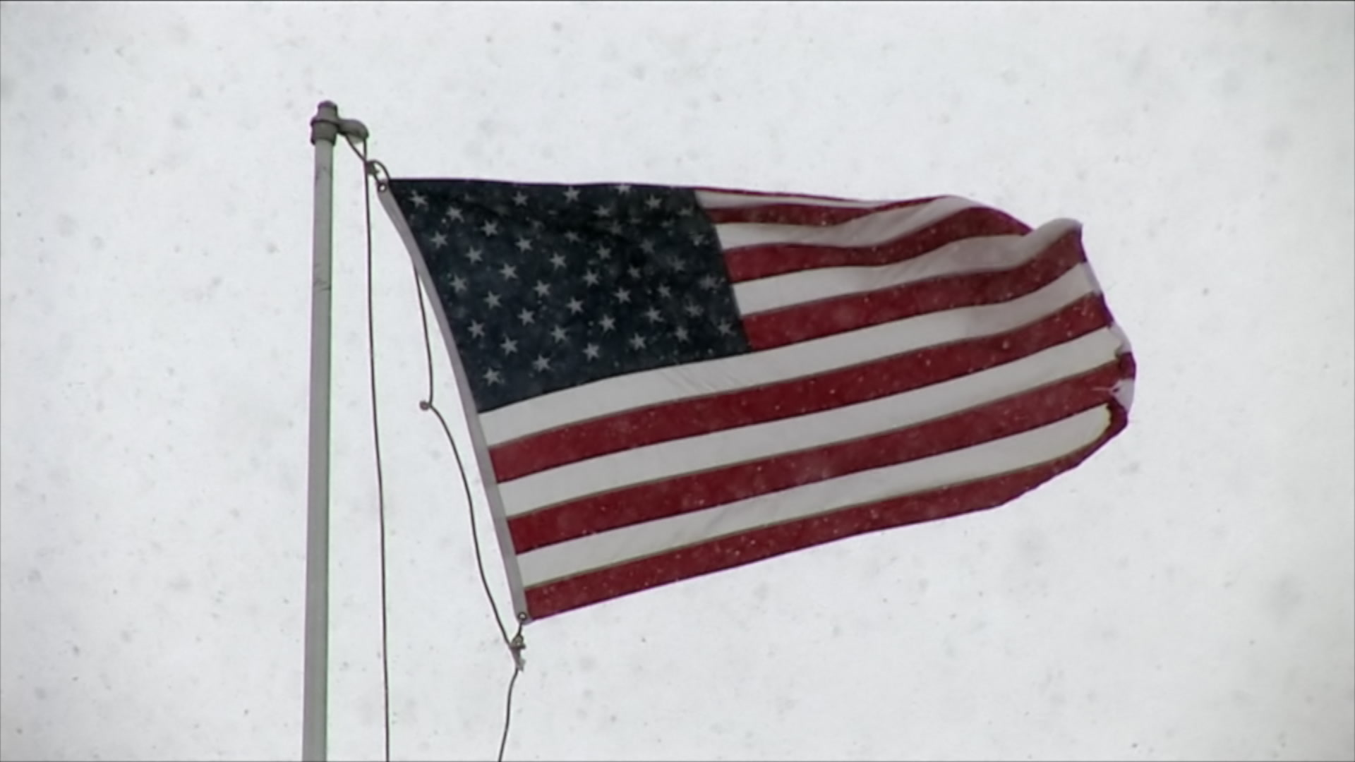 American flag blows as snow falls - winter storm, HD 1080
