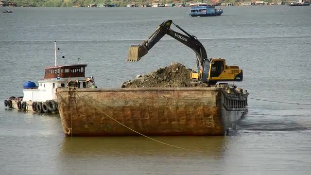 Time Lapse of Excavator on Barge Fills Dirt into Cambodian River - Phnom Penh Cambodia