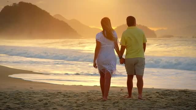 Brazilian couple walk down a beach in Brazil holding hands