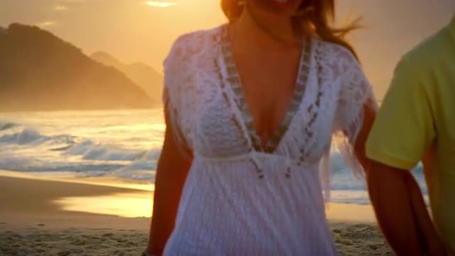 Brazilian couple walk down a beach in Brazil holding hands