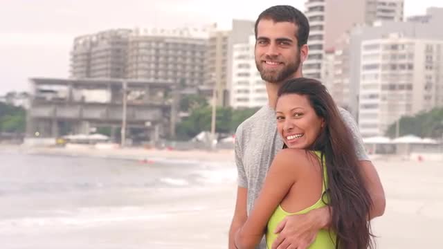 Brazilian couple embrace and look out over the ocean