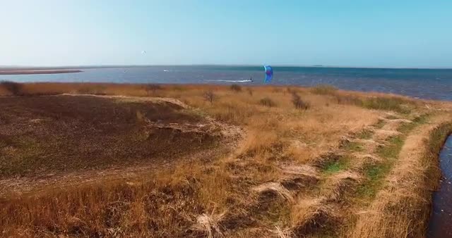 Kitesurfer Kiting On A Fjord Close To The Side Flyover Grass