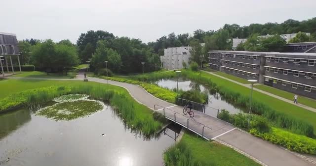 Biker Riding Between Lakes Over Small Bridge Followshot