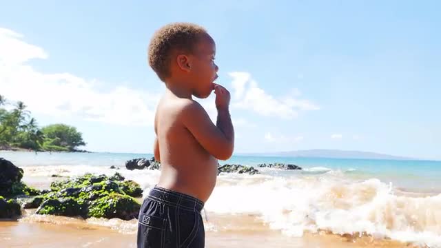 Black toddler playing in the ocean