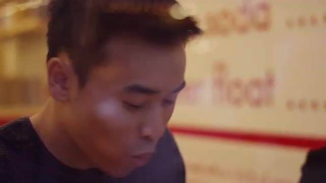 A young couple laughing and eating burgers and fries, through the window