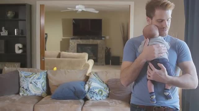 Father walking and bouncing newborn son in living room