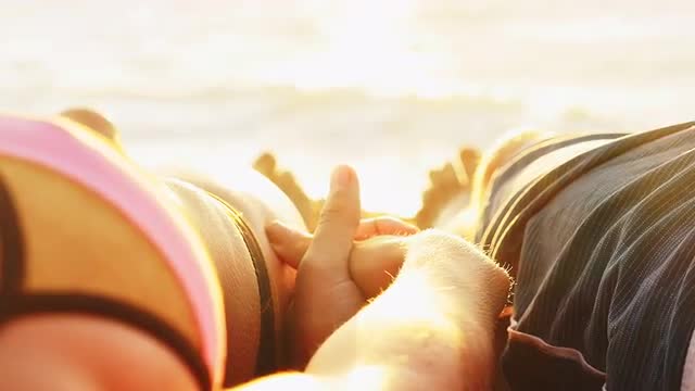 Couple holding hands on a beach at sunset