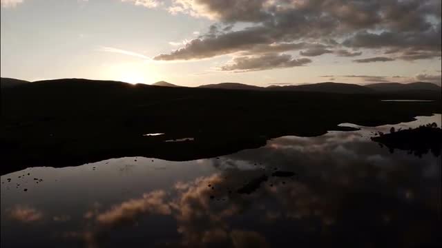 Aerial shot over Rannoch moor in Scotland revealing a desolute and baron landscape during sunset