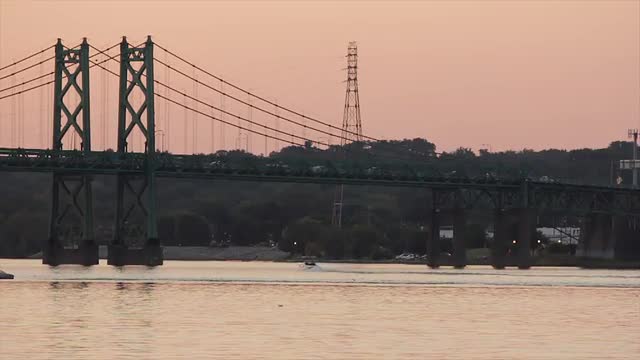 A speed boat glides under a Mississippi bridge