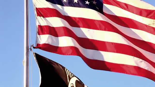 Tilting close-up shot of American and POW/MIA flags flying over Korean War Veterans Memorial