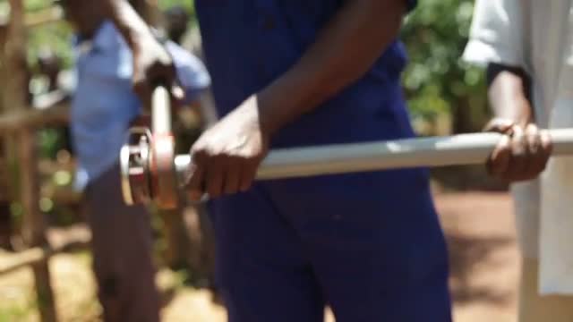 An African man threading a plastic tube used to install a new well in rural Uganda, Africa
