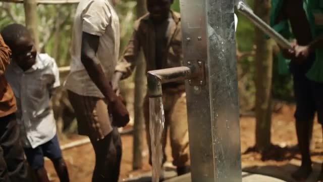 Happy African kids celebrate the installtion of a new water well in their village