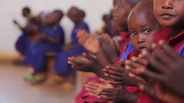 Young African school children singing and clapping in uniform