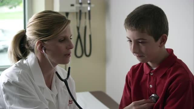 Slow motion of doctor listening to young boys heart.