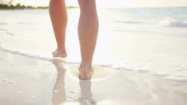 Legs of a Caucasian female walking barefoot on a beach 