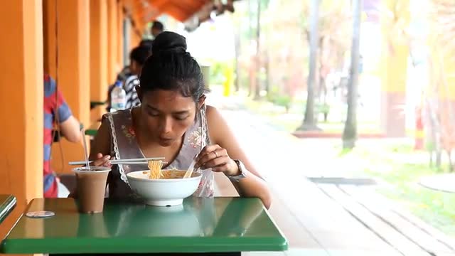 woman eating a bowl of noodles in a Chinese restaurant