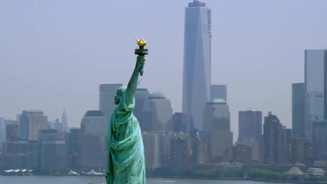MEDIUM AERIAL around Statue of Liberty with Jersey City and Manhattan in background