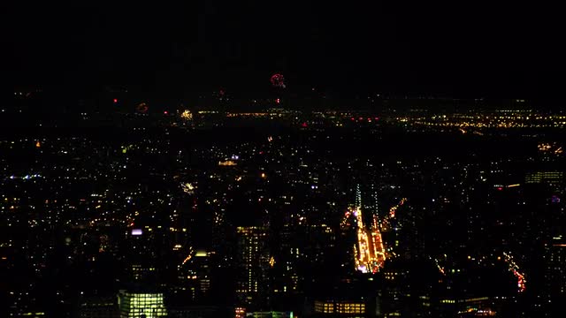 LONG AERIAL fireworks with cityscape in foreground