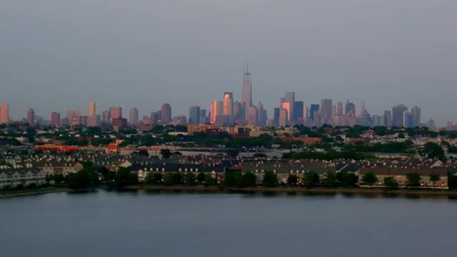 LONG AERIAL side POV Lower Manhattan skyline with residential waterfront New Jersey neighborhood in 