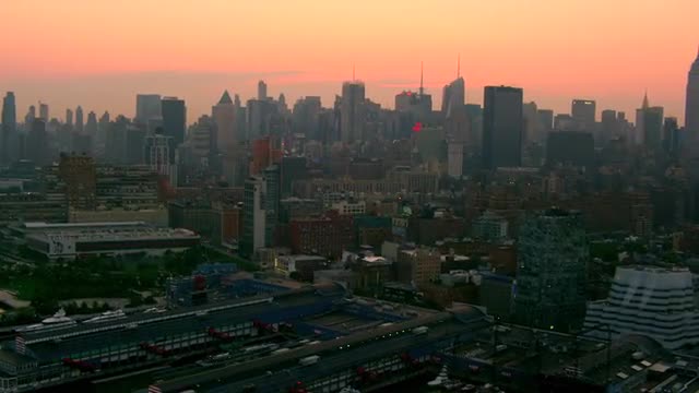 WIDE AERIAL POV over Hudson River waterfront and piers toward Midtown Manhattan at twilight