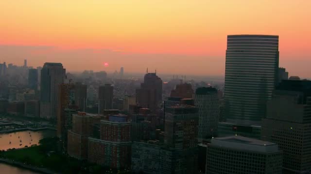 MEDIUM AERIAL SIDE POV past buildings in Financial District at sunrise