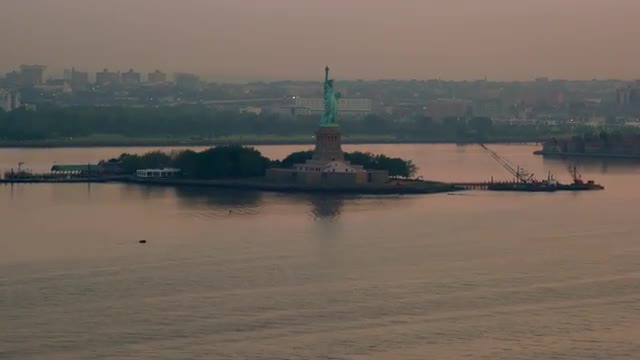 AERIAL POV over container ship to Statue of Liberty at sunrise