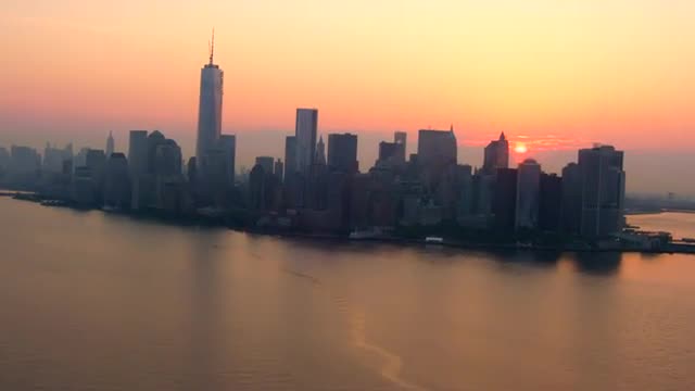 WIDE AERIAL TILT UP of Lower Manhattan skyline at sunrise