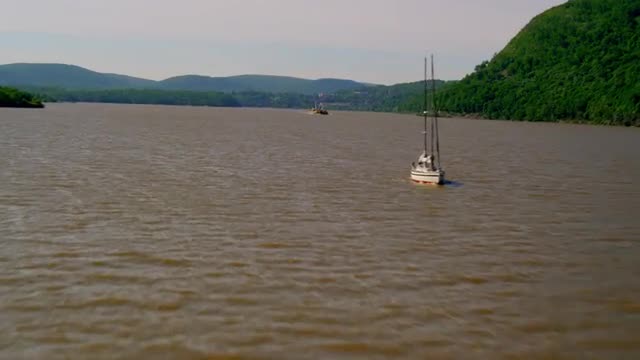 LONG AERIAL POV toward and past large sailboat on Hudson River