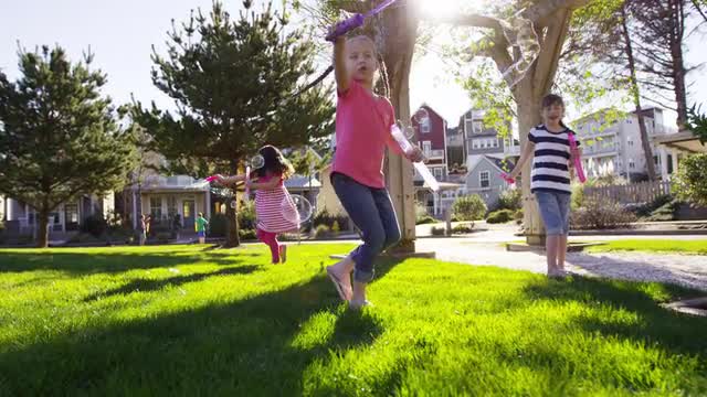 Children blowing bubbles at park, slow motion