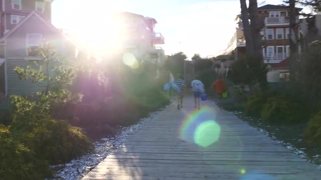 Three boys run up wooden pathway to beach
