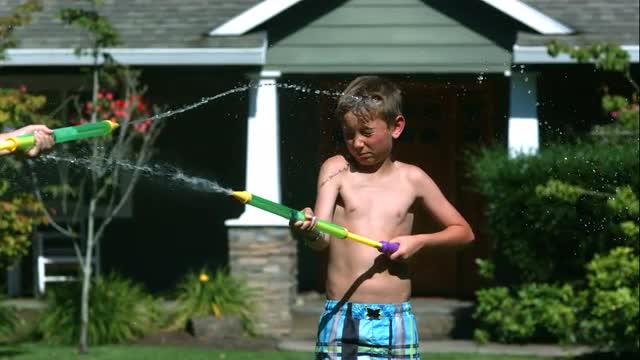 Two young boys having squirt gun fight in slow motion,  Shot with a Phantom Camera at 1000 frames pe