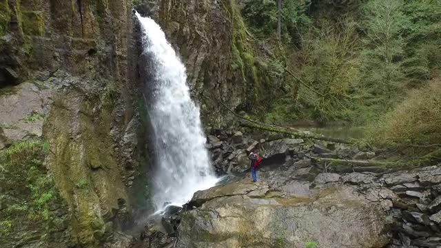 Aerial shot of backpacker taking photos of waterfall