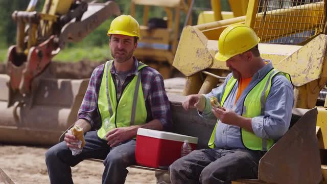 Two blue collar workers having lunch on job site