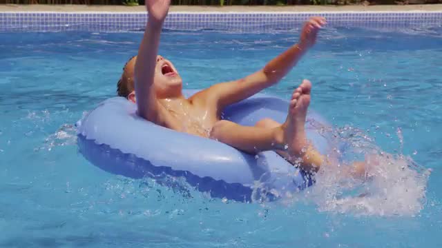 Young boy on innertube in pool.  Shot on RED EPIC for high quality 4K, UHD, Ultra HD resolution.