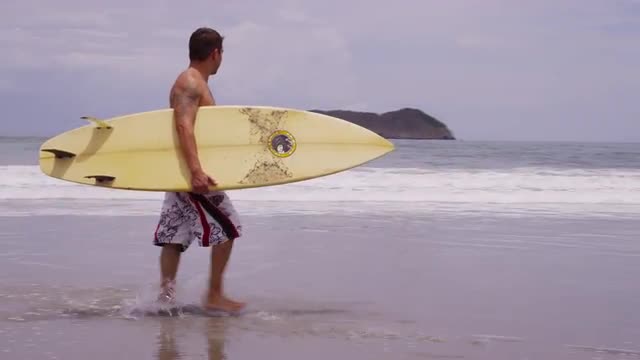 Surfer walking at beach. Shot on RED EPIC for high quality 4K, UHD, Ultra HD resolution.