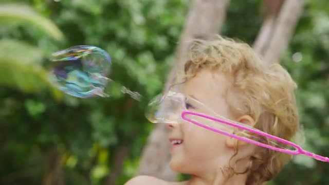 Young boy blowing bubbles. Shot on RED EPIC for high quality 4K, UHD, Ultra HD resolution.