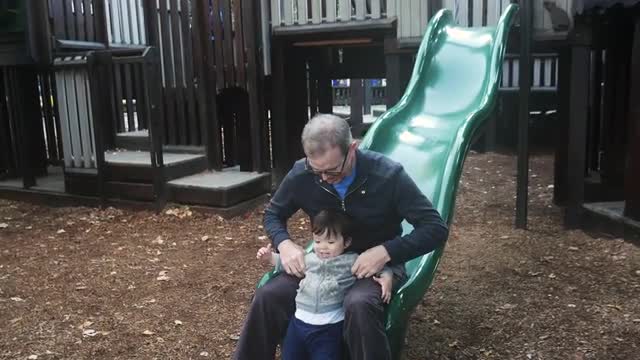 Caucasian Father and Toddler Daughter Going Down Slide Bottom of the Slide