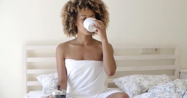 Attractive Woman With A Cup Of Coffee On The Bed