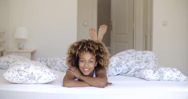 Cute african woman lying on bed and looking at camera.