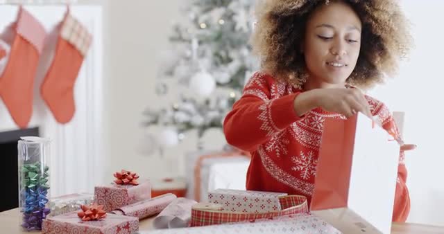 Pretty young woman wrapping Xmas presents