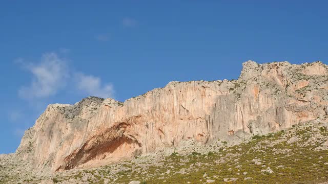 Low angle time lapse of clouds over cliff
