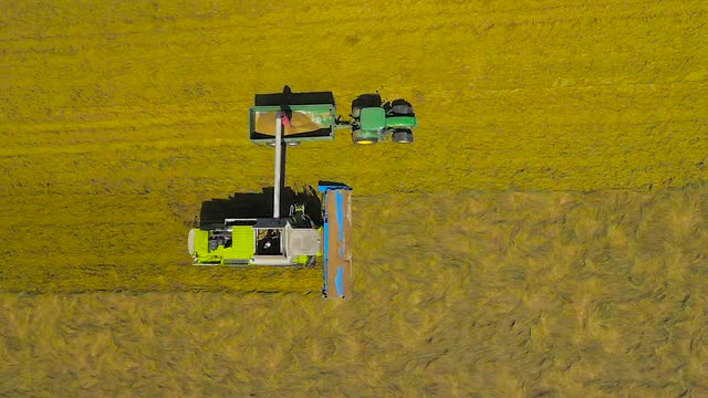 Aerial drone slow-motion footage of a combine harvester unloading