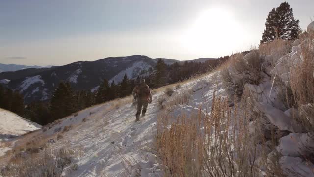 A Hunter walks along a Snowy Mountainside